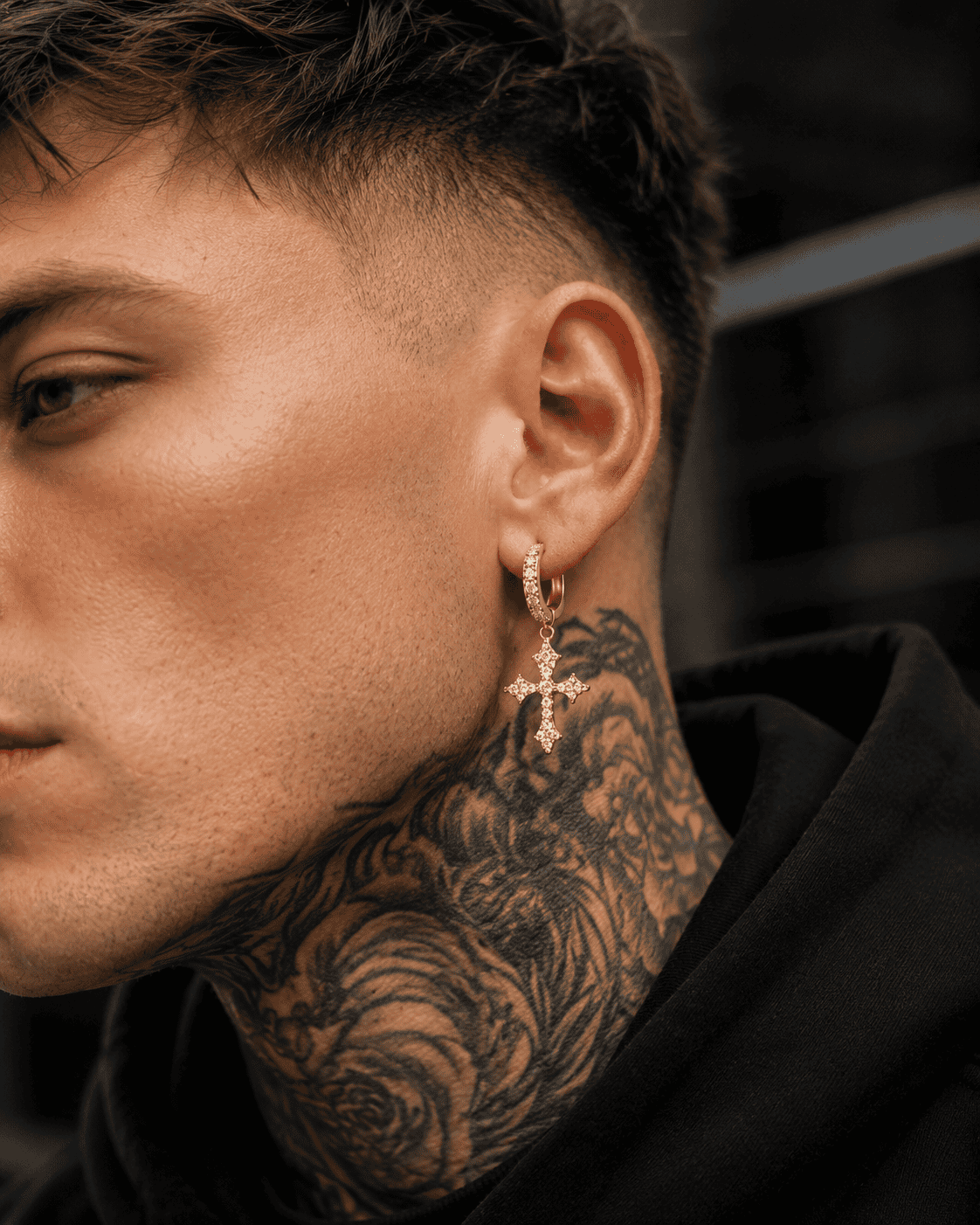 

Close-up of a stylish Black man wearing silver stainless steel cross hoop earrings with sparkling cubic zirconia stones, luxury men's streetwear jewelry, detailed side profile, modern fashion accessory.