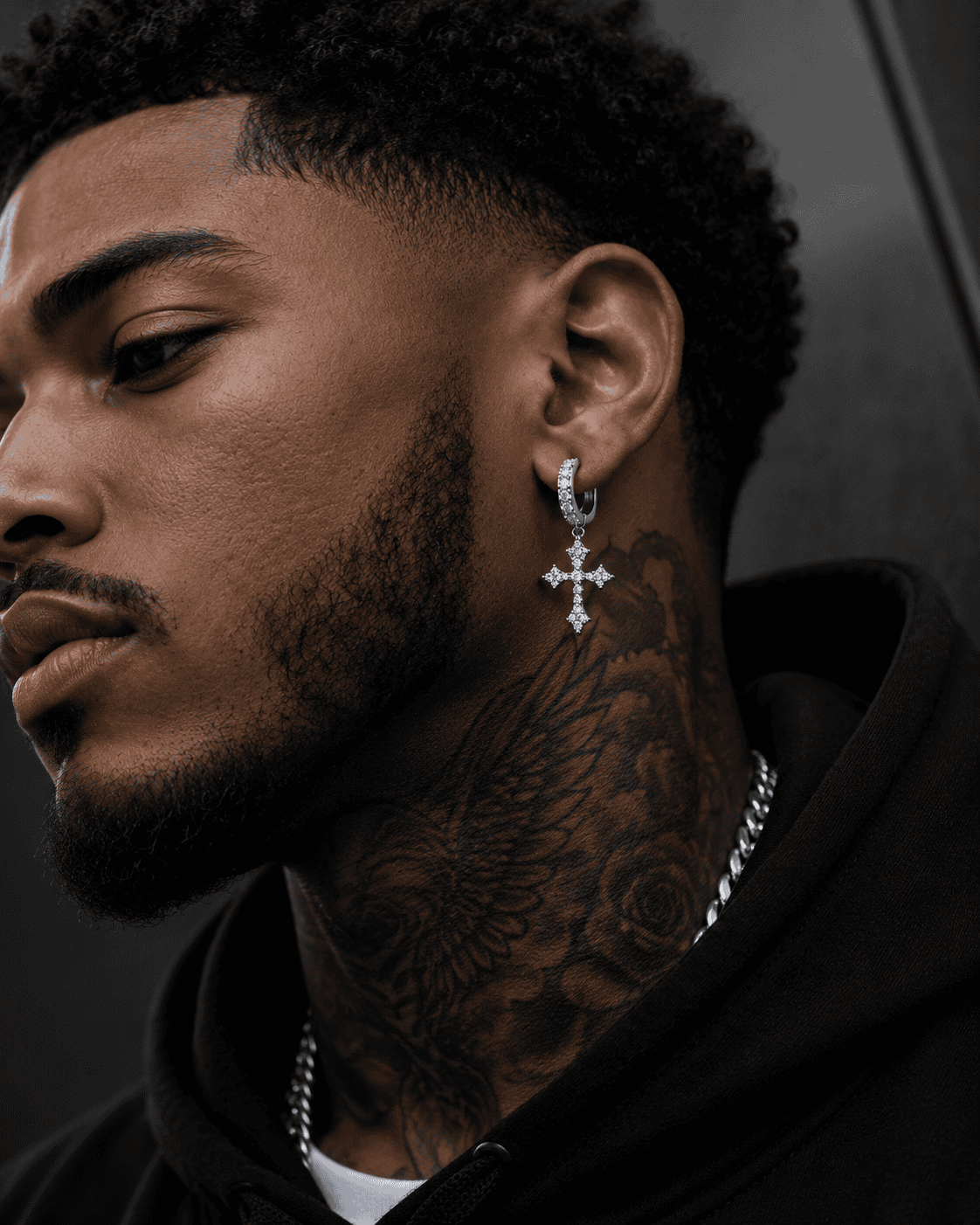 

Close-up of a stylish Black man wearing silver stainless steel cross hoop earrings with sparkling cubic zirconia stones, luxury men's streetwear jewelry, detailed side profile, modern fashion accessory.